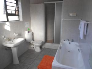 a bathroom with a white tub and a toilet and a sink at Buffalo View Lodge in East London