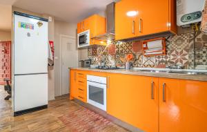 a kitchen with orange cabinets and a white refrigerator at Beautiful Home In Torre De Benagalbón in Torre de Benagalbón