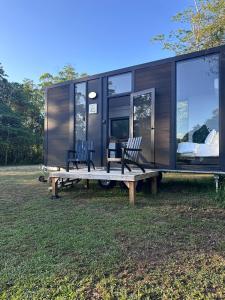 a tiny house with two chairs and a bench at The Dacious by Tiny Away in Midgenoo