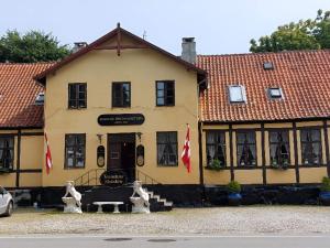 a yellow building with two statues in front of it at Queen suite in a hotel in Tranekær in Tranekær