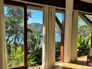 a room with a window with a view of the ocean at Vista para o Mar - Studio com 2 banheiros - Barra do Sahy in São Sebastião