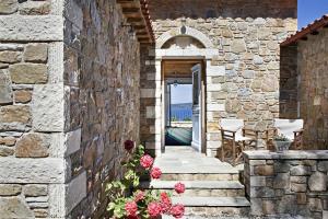a stone building with a pathway leading to a doorway at Lithea Villas and Studios by the Sea in Aghios Petros Alonissos