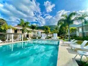 PaeaTahatai - Private beach, pool, AC, High speed net的一个带白色椅子和棕榈树的游泳池