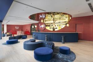 a lobby with blue stools and a red wall at Riva Vibe Hotel Bangkok by PCL in Bangkok +51 photos