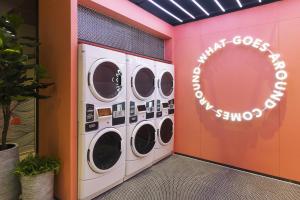 a laundry room with four washer and dryer machines at Riva Vibe Hotel Bangkok by PCL in Bangkok