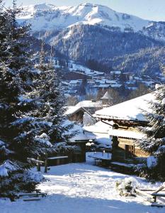 una montaña cubierta de nieve con una casa y árboles en Les Fermes de Marie, en Megève