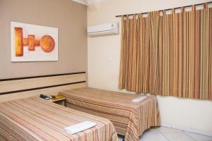 a hotel room with two beds and a window at Plaza Dutra Hotel in Caçapava