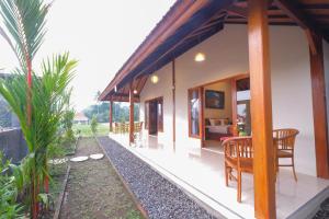 a house with a table and chairs on the side at Uma Sri Dewi Villa Ubud in Ubud