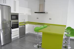 una cocina con encimera verde y taburetes. en Apartamentos Turísticos Clavero, en Almagro