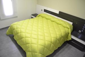 um quarto com um edredão amarelo numa cama em Apartamentos Turísticos Clavero em Almagro