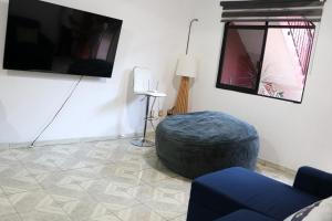 a living room with a blue ottoman and a television at Departamento Bugambilias in Oaxaca City