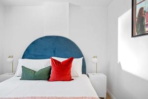 a white bed with a blue headboard and red pillows at Central Chic Stay in Perth