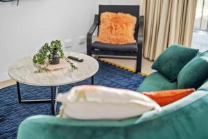 a living room with two green chairs and a table at Central Chic Stay in Perth