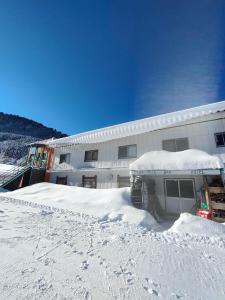 un edificio con nieve en el suelo delante de él en Guest House Shiroikiseki, en Toyama