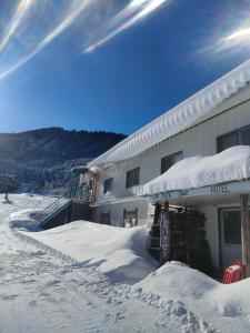 Un edificio cubierto de nieve con nieve en el suelo. en Guest House Shiroikiseki, en Toyama