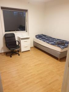 a bedroom with a bed and a chair and a window at Tevlingveien 9 in Alnabru