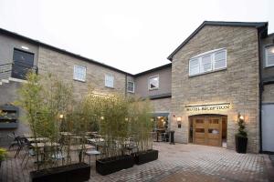 un edificio de ladrillo con un patio con mesas y árboles en Jolly's Hotel Wetherspoon en Dundee