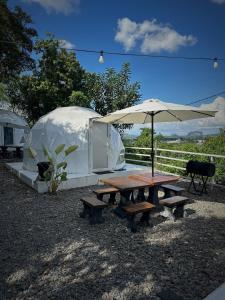 a picnic table with an umbrella and a tent at Gunung Medan Glamping & Cafe in Kangar