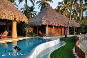 a resort with a swimming pool and a hut at Casa Los Cocoteros in Gallinero