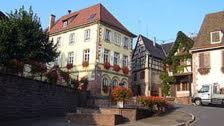 un grand bâtiment blanc avec un toit rouge dans l'établissement Au Fief du Château, à Orschwiller