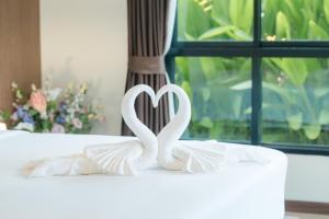 zwei weiße Schwäne bilden ein Herz auf einem Bett in der Unterkunft Thebeyonder house Pattaya, Pet friendly in Ban Huai Yai