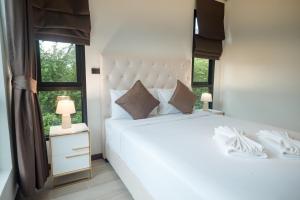 ein Schlafzimmer mit einem großen weißen Bett und einem Fenster in der Unterkunft Thebeyonder house Pattaya, Pet friendly in Ban Huai Yai