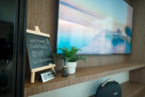 eine Tafel auf einem Regal mit Pflanzen und einem TV in der Unterkunft Thebeyonder house Pattaya, Pet friendly in Ban Huai Yai + 26 Fotos