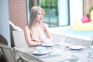 eine Frau, die an einem Tisch in einem Restaurant sitzt in der Unterkunft Thebeyonder house Pattaya, Pet friendly in Ban Huai Yai