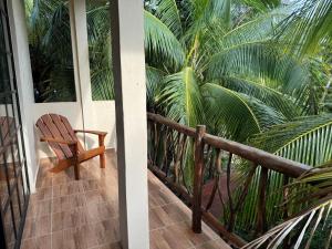une chaise en bois assise sur une terrasse couverte avec des palmiers dans l'établissement Casa Jardin del Amor, à Tulum