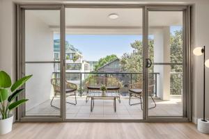 ein Wohnzimmer mit Glasschiebetüren, die auf eine Terrasse führen in der Unterkunft Urban Rest Bondi Beach in Sydney