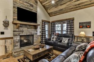 a living room with a leather couch and a fireplace at French Kisses in Ellijay