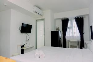 a bedroom with a white bed with two slippers at Minimalist Studio Room at Urbantown Serpong Apartment By Travelio in Tangerang