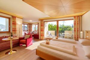 a bedroom with a large bed and a living room at Hotel Winzerhof in Termeno +52 photos