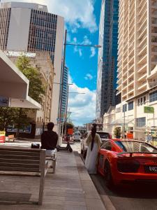 Un paio di persone che camminano lungo un marciapiede vicino a un'auto di Garden Hostel ad Auckland