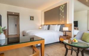 a hotel room with a large bed and a table at Dusit Princess Chiang Mai in Chiang Mai