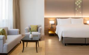 a hotel room with a bed and a couch and a table at Dusit Princess Chiang Mai in Chiang Mai