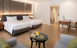 a hotel room with two beds and a table at Dusit Princess Chiang Mai in Chiang Mai