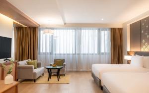 a hotel room with a bed and a couch and a chair at Dusit Princess Chiang Mai in Chiang Mai