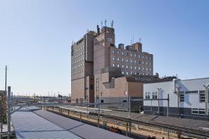 un edificio con una torre de reloj junto a una estación de tren en Saitama Grand Hotel Honjo, en Honjo