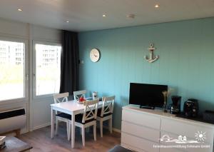 a dining room with a table with chairs and a tv at 06 Ferienwohnung Heimathaven App.68-112 in Burgtiefe auf Fehmarn 