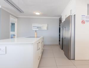 Una cocina con gabinetes blancos y un refrigerador de acero inoxidable. en Vallen Lodge 2 With Inverter, en Ballito 27 fotos más