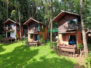 a group of cottages in the woods with green grass at บ้านต้นไม้แม่กำปอง Baan TONMAI MAEKAMPONG in Chiang Mai