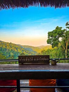 a bench with a view of the mountains at บ้านต้นไม้แม่กำปอง Baan TONMAI MAEKAMPONG in Chiang Mai