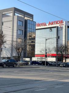 a hotel entrance with cars parked in a parking lot at Apartament in Craiova