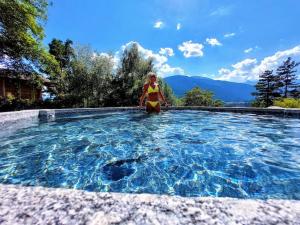 a woman in a swimsuit sitting in a swimming pool at La terrazza sul Vallecetta in Santa Lucia