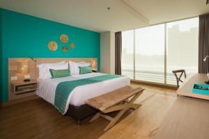 - une chambre avec un grand lit et un mur vert dans l'établissement bh Barranquilla, à Barranquilla