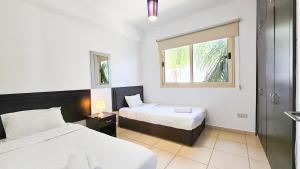 a hotel room with two beds and a window at Palmvibes Villa in Paralimni