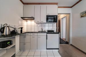 a kitchen with white cabinets and a microwave at Paradies 012 in Arosa