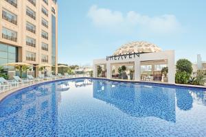 a large swimming pool in a hotel with a building at Barcelo Al Jaddaf, Dubai in Dubai