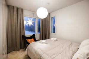 a bedroom with a bed and a chair and a window at Villa Nightsky -private location, sauna and jacuzzi in Rovaniemi